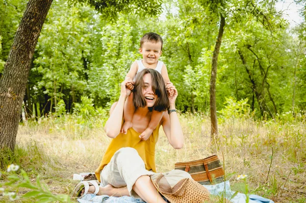 快乐的母亲抱着儿子在野餐的肩膀上 — 图库照片