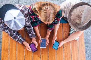 overhead view of young friends using smartphones with social media apps clipart
