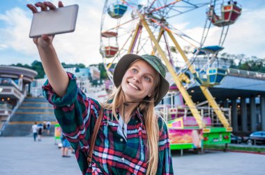 Selfie smartphone ile eğlence parkında alarak gülümseyen güzel sarışın kız