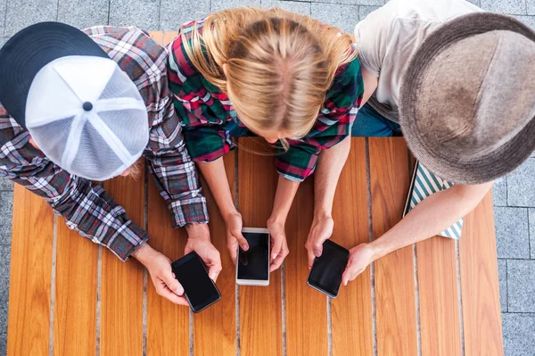 Overhead View Young Friends Using Smartphones Blank Screens Wooden Table — Free Stock Photo