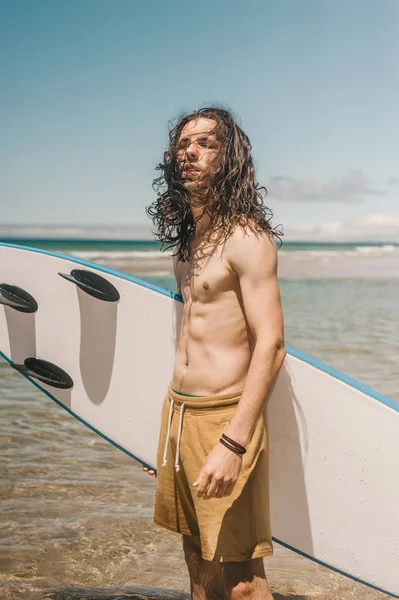 Retrato de jovem com prancha de surf em pé no oceano no dia de verão — Fotografia de Stock