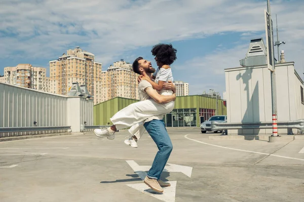 Feliz jovem casal multicultural abraçando e se divertindo juntos na rua — Fotografia de Stock