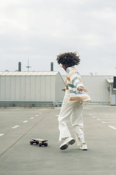 Jeune femme américaine africaine s'amuser avec skateboard sur la rue — Photo de stock