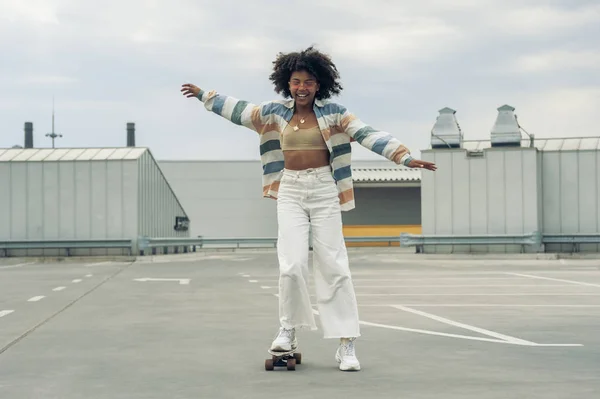 Feliz joven afroamericana mujer skateboarding en la calle - foto de stock