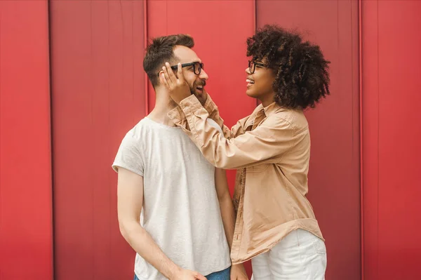 Lächelnde junge afrikanisch-amerikanische Frau, die ihrem hübschen Freund eine Brille anpasst — Stockfoto