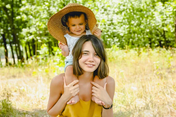 Happy mother holding son on shoulders and looking at camera — Stock Photo