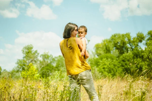 Madre che tiene il figlio in campo nella giornata di sole — Foto stock