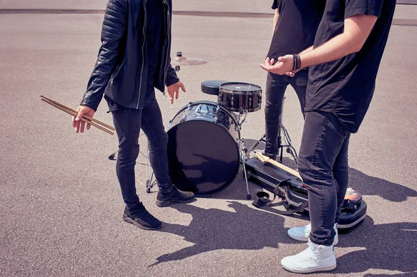 Vista parcial de la banda de rock en ropa negra de pie cerca de instrumentos musicales en la calle - foto de stock