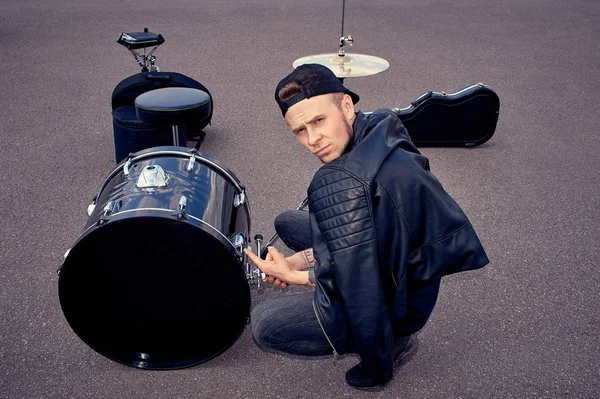 Baterista em roupas pretas apontando para kit de bateria na rua — Fotografia de Stock