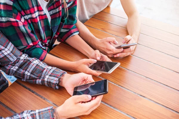 Recortado disparo de amigos jóvenes utilizando teléfonos inteligentes con pantallas en blanco - foto de stock
