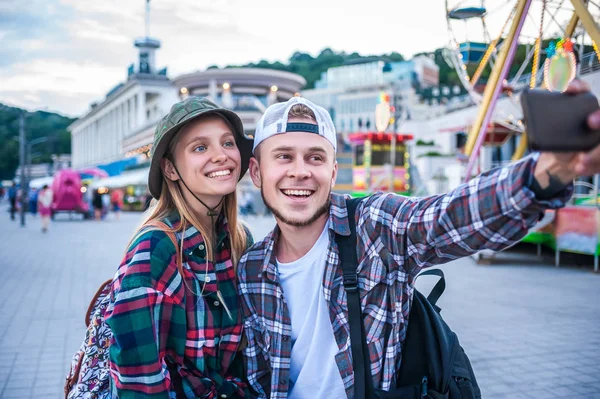 Feliz jovem casal tomando selfie com smartphone no parque de diversões — Fotografia de Stock