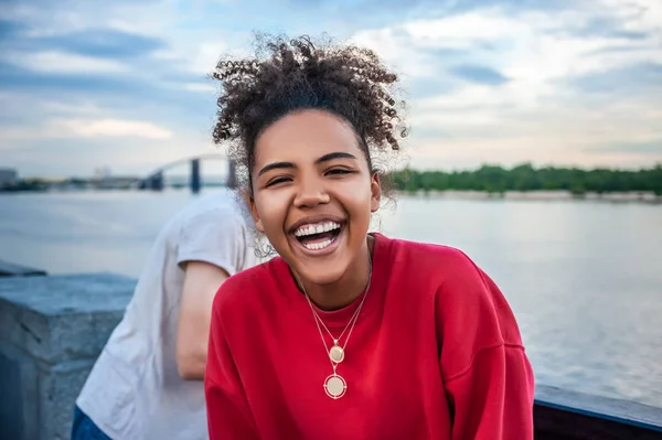 Hermosa joven afroamericana feliz riéndose en la orilla del río - foto de stock