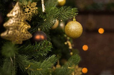 İçinde belgili tanımlık geçmiş bulanık ışıklı kahverengi oyuncaklar Noel ağacı süslenmiş.