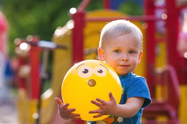 Sarı topu onun elinde tutan ve gülümseyen küçük çocuk