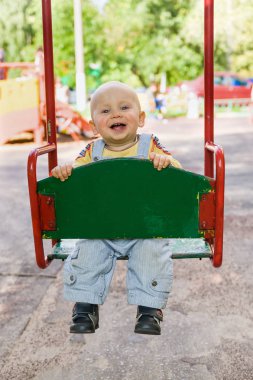 küçük çocuk bir gülümseme ve yapışkanlık dışarı dil ile bir salıncak üzerinde sallanan