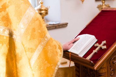 Bir rahip İncil'de bir ele sahip sarı cüppeli