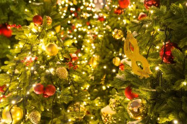 Kırmızı ve altın Noel süsleri ve topları sarı çelenk ile Noel ağacı üzerinde