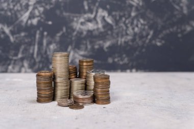 Rus bir gri beton zemin ve koyu gri arka plan üzerinde farklı yükseklikte sikkeleri yığınları