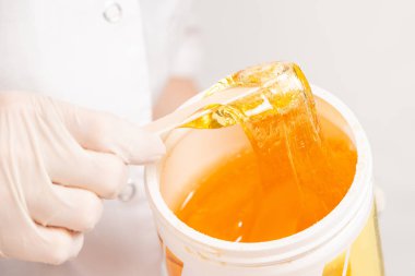 Depilasyon beyaz lateks eldiven ustası bir tahta sopa şeker hamur kavanoz gelen ortaya çıkarır