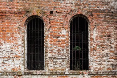 İki pencere açıklıklar metal çubuklarla eski kırmızı tuğla duvar