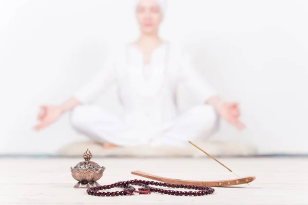Indian accessories for meditation and yoga, prayer beads, oil burner, incense in the background of the meditator girls