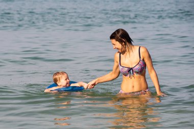 Genç anne oğluyla denizde yüzüyor.