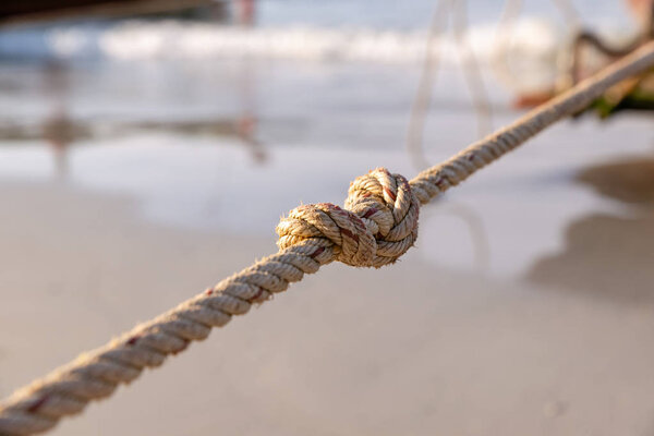 Rope, with a single tight knot, suspended horizontally in the air, against black background