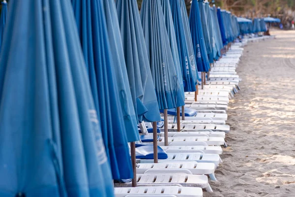 row of beach beds with blue umbrellas