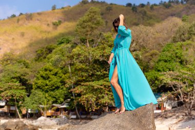 bir taş deniz plajında mavi bir tunik kız