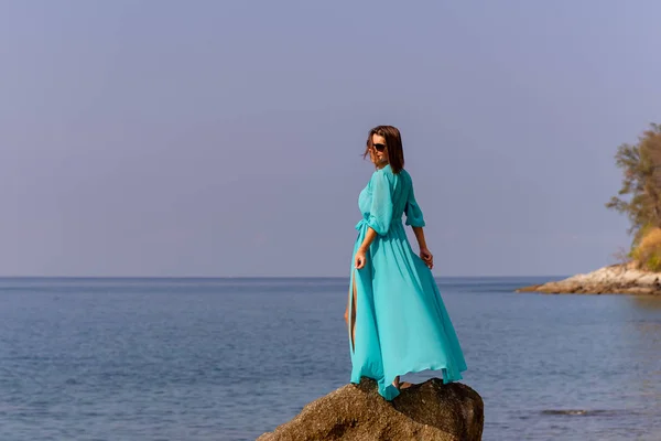 Chica en una túnica azul en una playa de piedra — Foto de Stock