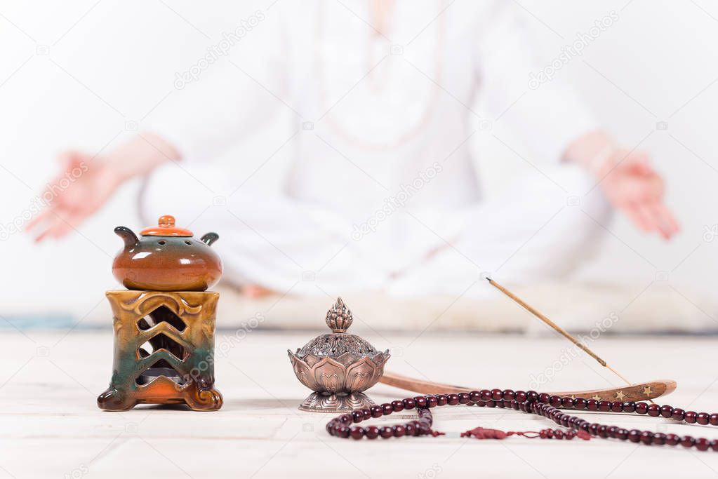 Indian accessories for meditation and yoga, prayer beads, oil burner, incense in the background of the meditator girls