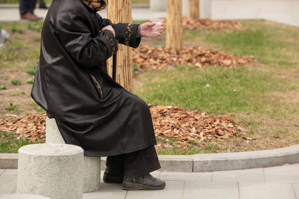 Mujer sin hogar en la calle mendigando con una taza de plástico en la mano — Foto de Stock
