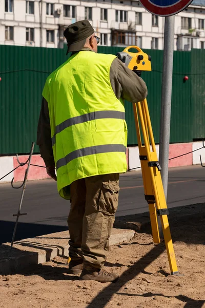 Surveyor dalam rompi kuning di tempat kerja di lokasi konstruksi — Stok Foto