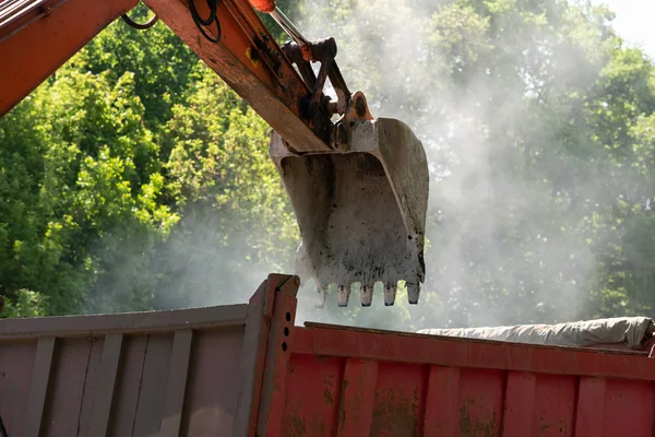 Descarga de asfalto crudo caliente desde el camión con la ayuda de una excavadora — Foto de Stock