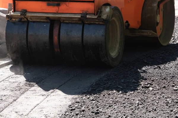Orange road roller compacts fresh hot black asphalt with gravel — Stok Foto
