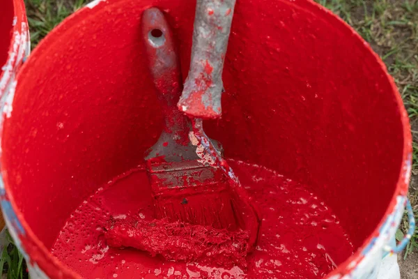 Roller dan sikat dalam ember plastik dengan cat merah — Stok Foto