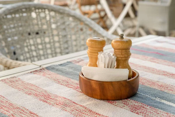 餐厅夏季露台桌上放着胡椒、盐瓶、餐巾和牙签的木制摊位 — 图库照片