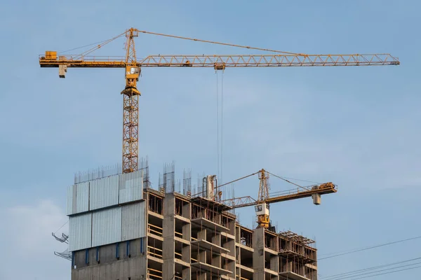 Site in opbouw. Bouw kranen en hoogbouw bouwen aanbouw tegen blauwe hemel. — Stockfoto