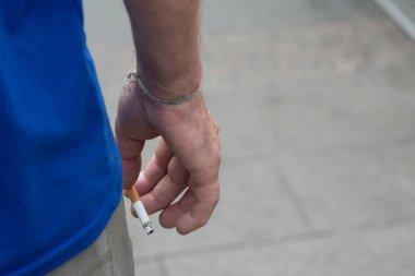 Genç adamın elinde dumanlı bir sigara var. Sigara içmenin zararı yok. Uzayı kopyala.