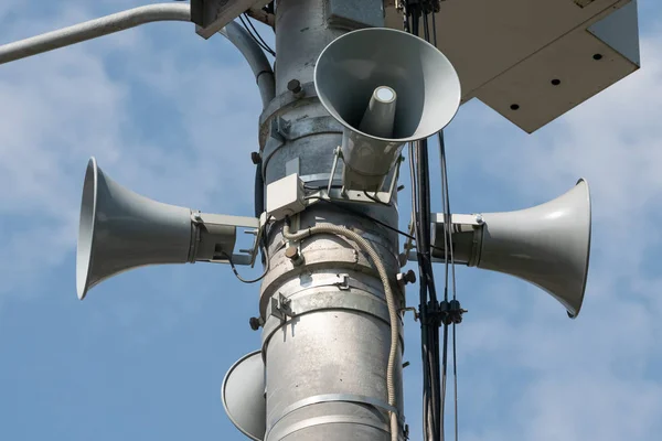 Drei Lautsprecher auf Mast gegen blauen Himmel — Stockfoto