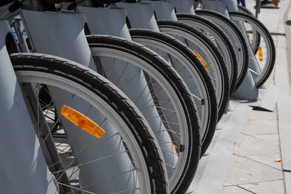 Wheels of parked bikes in the bike rental Parking lot.Bike hire pick up station.Rent a bike cheaply.Bicycle wheel in the perspective of the shot.Parking with bicycles.Sustainable urban transport — Stock Photo, Image