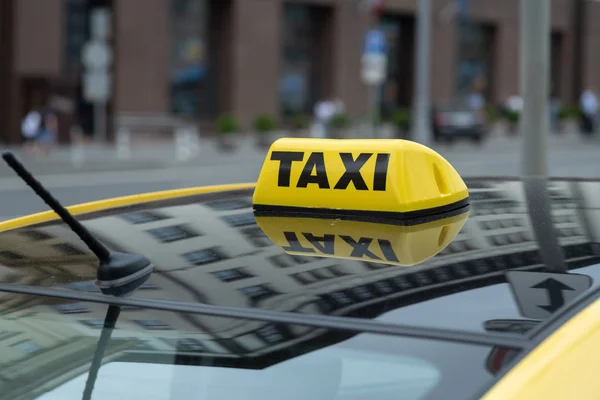 Żółta kabina ze znakiem taksówki na dachu zaparkowanym na ulicy miasta czeka na podniesienie pasażerów.Taksówka zaparkowana jest na ulicy dużego miasta.Skup się na żółtej ikonie lampy — Zdjęcie stockowe