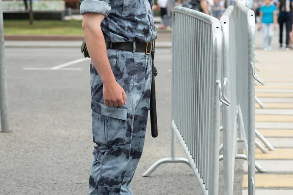 Поліцейський з паличкою біля металевого паркану, крупним планом — стокове фото