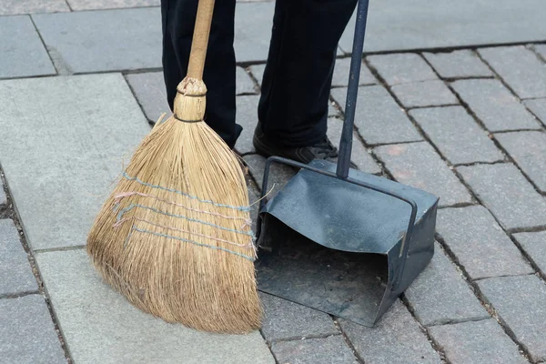Municipal worker sweep the road with broomstick and collects garbage in scoop. sanitation worker sweep street — Stock Photo, Image