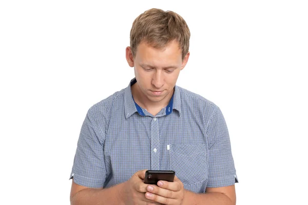 Молодой человек, стоящий, глядя на экран телефона, болтая с другом, одетый в синюю рубашку на белом фоне — стоковое фото
