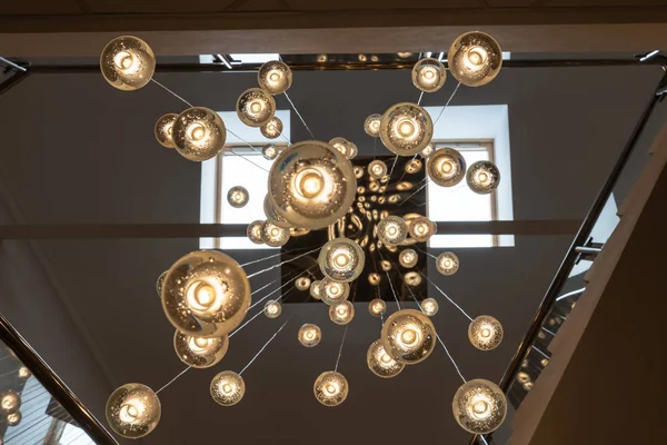 Muitas lâmpadas que descem com seus cabos do teto criando uma ilusão óptica única . — Fotografia de Stock