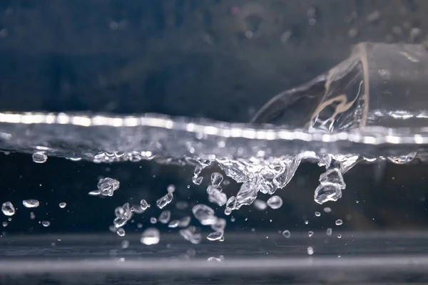 Verter agua salpicada con burbujas de aire en fondo azul de agua blanca — Foto de Stock