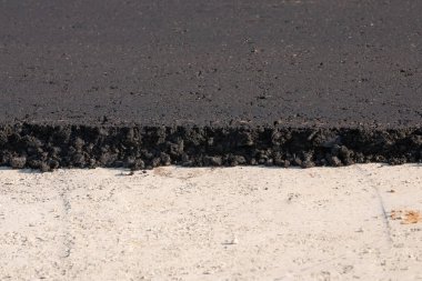 yapıgösteren çakıl yüksek bir kenar ile taze döşenmiş siyah bitüm asfalt.