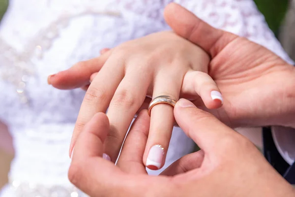 Love and marriage. Wedding ceremony. Close up of groom putting golden ring on the bride\'s finger.