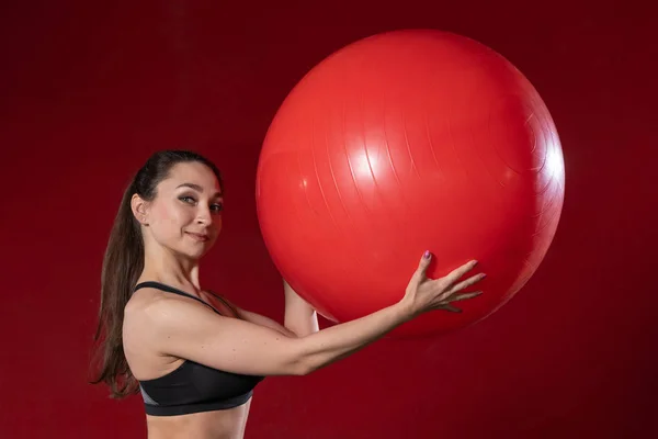 Retrato de una joven sosteniendo un ejercicio de pelota suiza y sonriendo a la cámara. Imagen del modelo fitness femenino en vivo — Foto de Stock